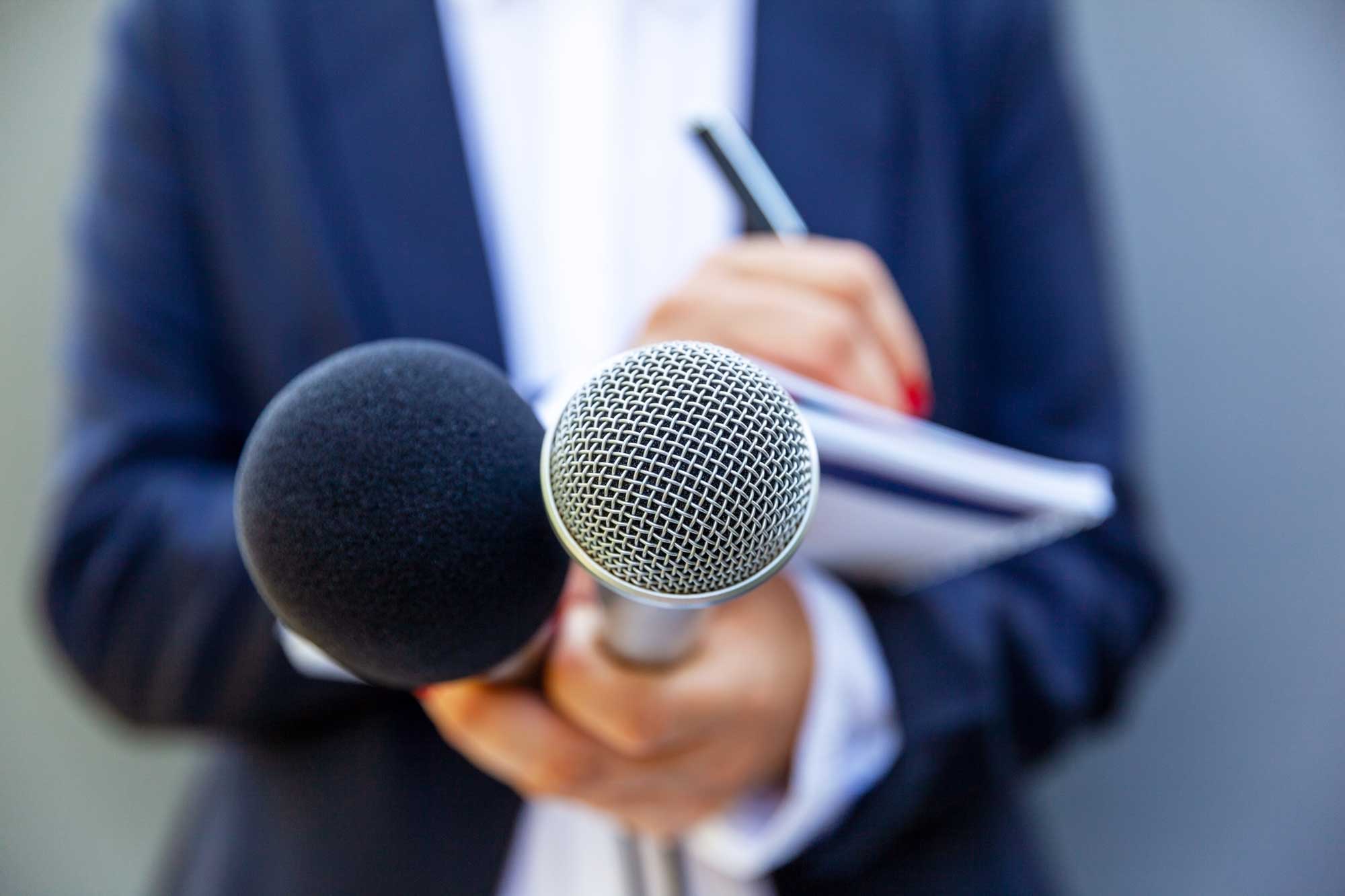 Female journalist at news conference or media event, writing notes